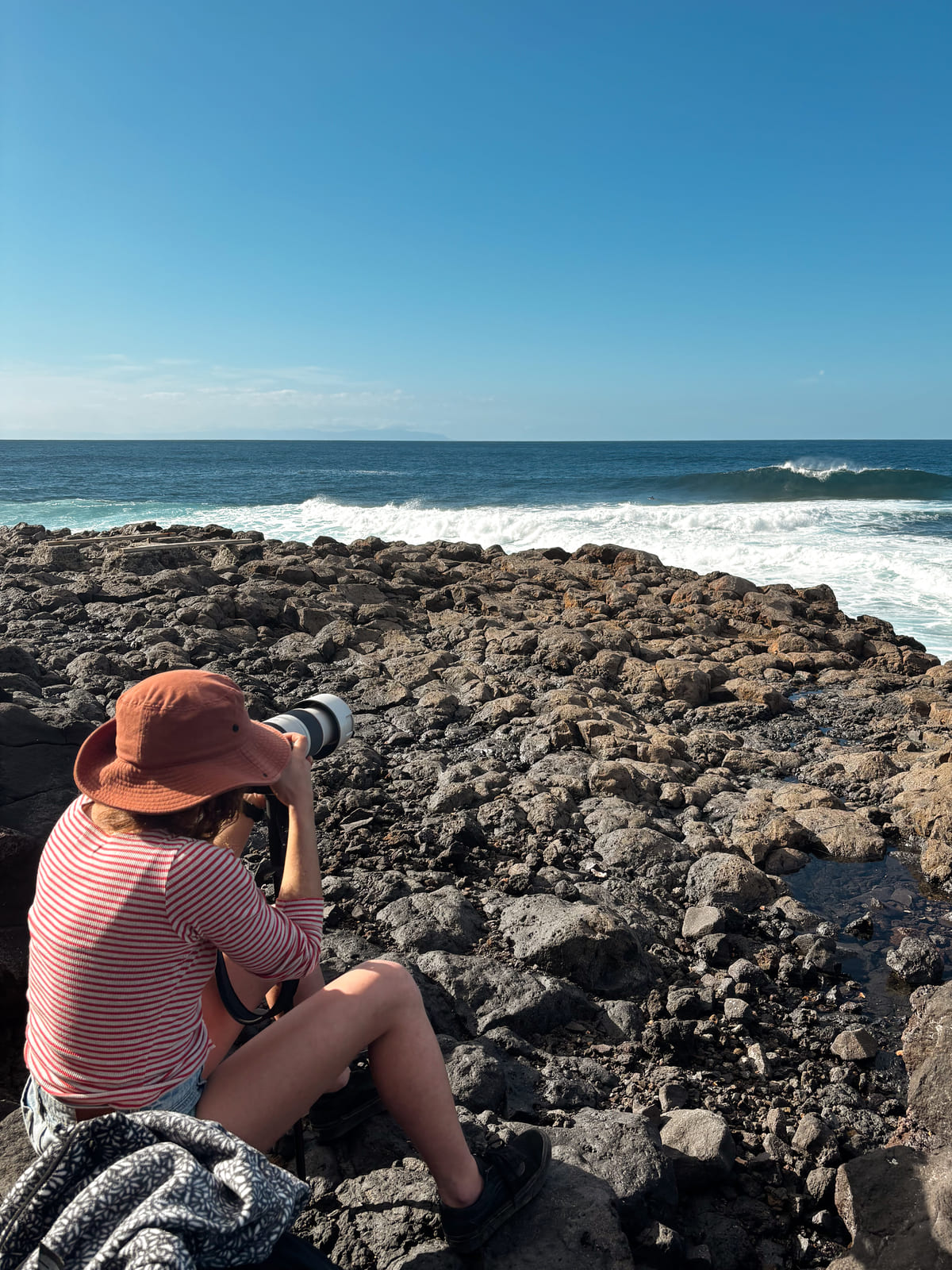 Júlia Miralles, sacando fotos en “El Frontón” en Gran Canaria. Uno de sus escenarios para fotografía favoritos; ¡Las olas! Fotografía: Lugares de Aventura. Autor: Llorenç Binimelis.